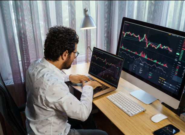 istock Businessman analyzing crypto currency market graphs on computer and laptop screen at home. Bitcoin / Cryptocurrency concept 1361074687