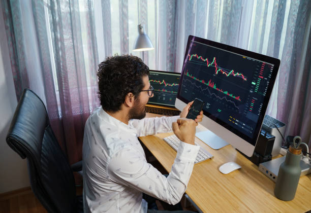 istock Businessman analyzing crypto currency market graphs on computer and laptop screen at home. Bitcoin / Cryptocurrency concept 1361074696