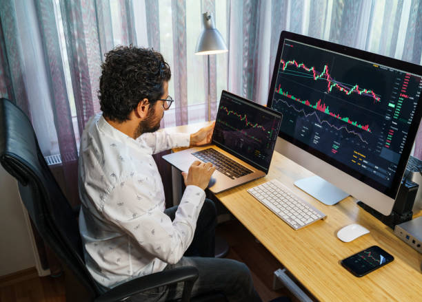 istock Businessman analyzing crypto currency market graphs on computer and laptop screen at home. Bitcoin / Cryptocurrency concept 1361074698