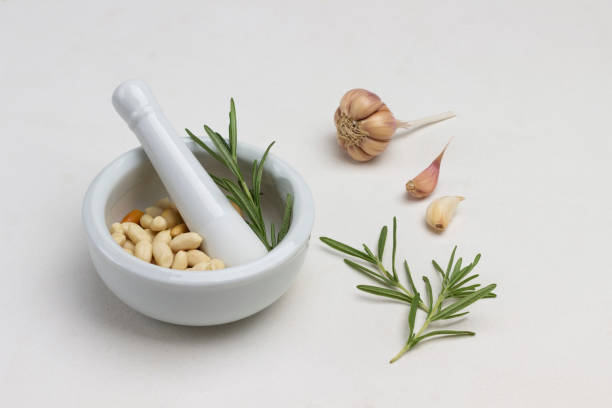 nuts in mortar. rosemary and garlic on table. - mortar and pestle spice seasoning coriander seed imagens e fotografias de stock