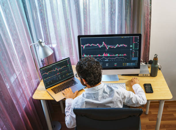 istock Businessman analyzing crypto currency market graphs on computer and laptop screen at home. Bitcoin / Cryptocurrency concept 1361085708