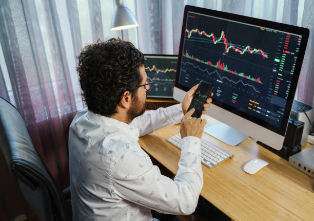 istock Businessman analyzing crypto currency market graphs on computer and laptop screen at home. Bitcoin / Cryptocurrency concept 1361085715
