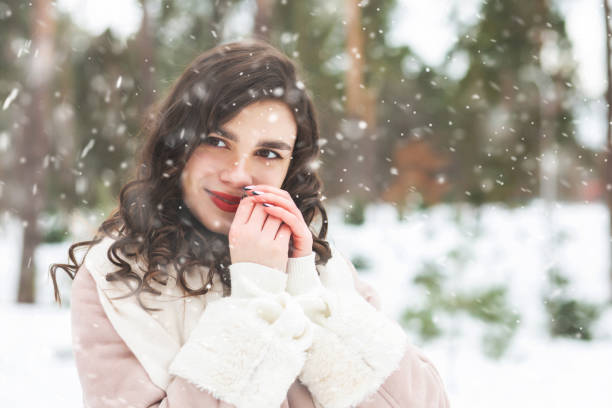istock Charming curly lady walking at the park with snowflakes 1361086063