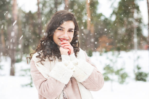 istock Joyful curly lady walking at the park with snowflakes 1361086067
