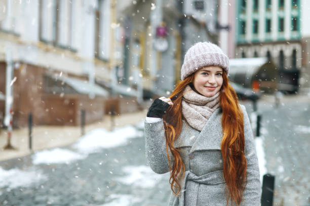 элегантная рыжеволосая дама гуляет по городу во время новогодних каникул - journey grace clothing snow стоковые фото и изображения