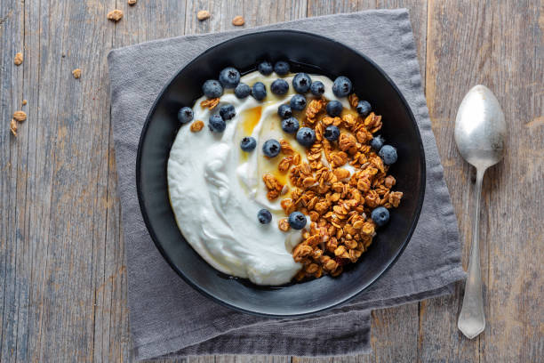 Homemade granola muesli with yogurt Appetizing homemade muesli with berries and yogurt served in bowl on wooden background. greek yogurt photos stock pictures, royalty-free photos & images
