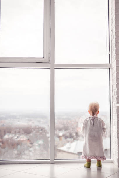 istock Cute little child looking at the large window 1361090636