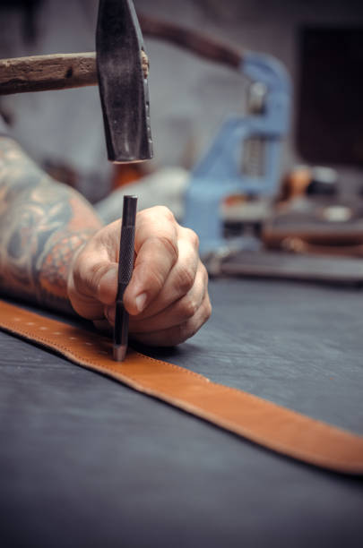 istock Handicraftsman performs leather working for a new product in leather shop 1361092101