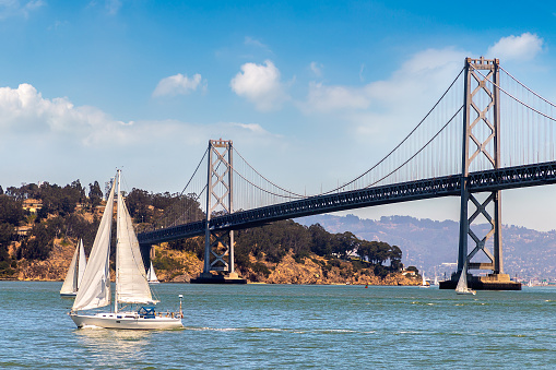 Sailing yacht against Oakland Bay Bridge in San Francisco, California, USA