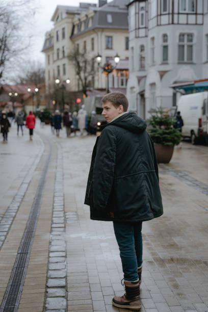 istock a young guy walks forward in a winter black jacket, slightly turned around and looked to the side 1361093816