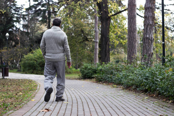 Senior man walking and relaxing in park. Walking away, relaxing, rear view