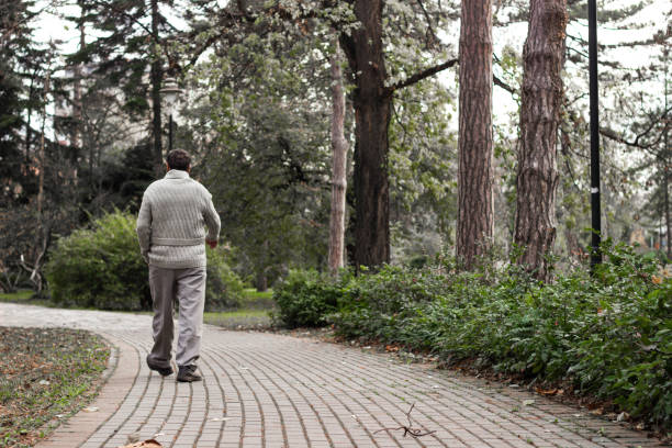 Senior man walking and relaxing in park. Walking away, relaxing, rear view