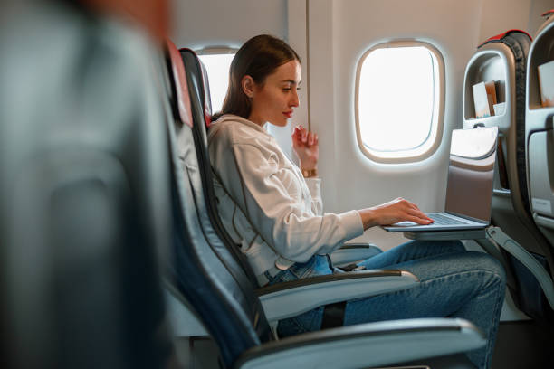 istock Female traveler using laptop in passenger airplane 1361095723