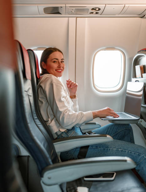 istock Joyful young woman using notebook in airplane 1361095725