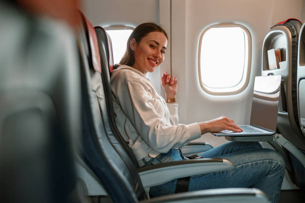 istock Cheerful young woman using notebook in airplane 1361095728