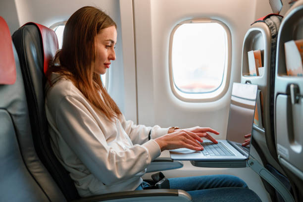 istock Young woman using laptop in passenger airplane 1361095733
