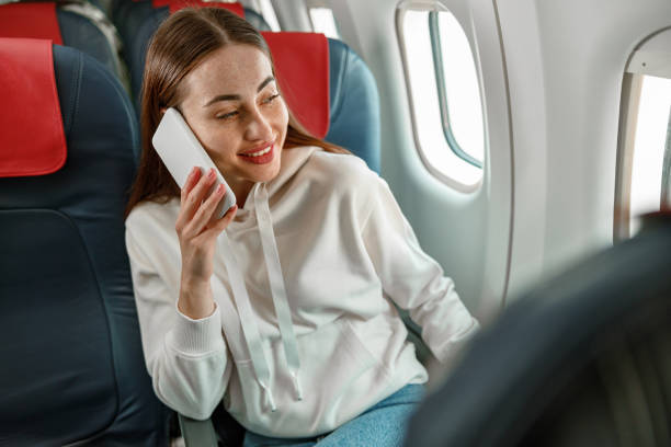 istock Cheerful young woman talking on cellphone in airplane 1361095739