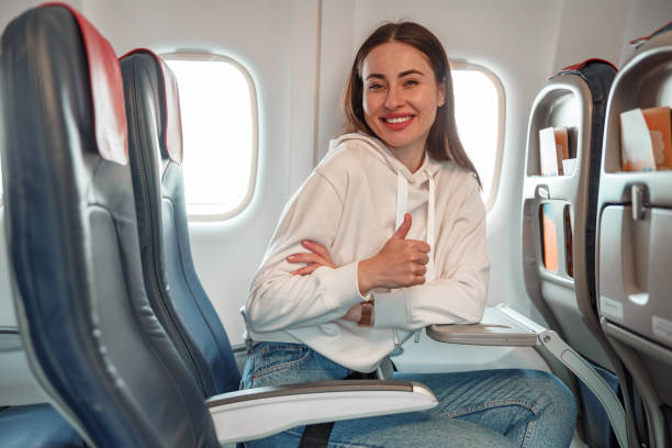 istock Joyful young woman doing thumbs up gesture in airplane 1361095747
