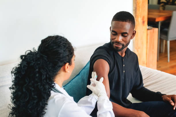 istock Doctor vaccinating young man at home 1361096022