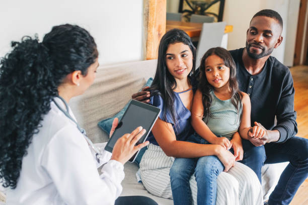 Young family getting medical consultation from doctor on house call Young family sitting on sofa listening to the advice from a female doctor using digital tablet. Doctor on house call giving medical consultation to a young family. medical insurance stock pictures, royalty-free photos & images