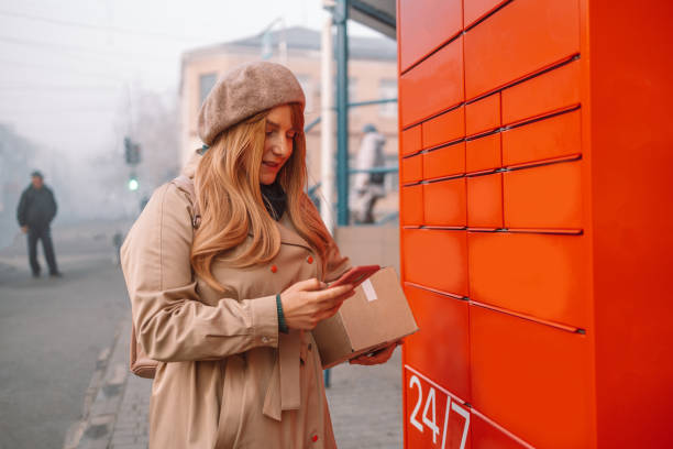 istock Woman picks up mail from automated self-service post terminal machine. Mail shipping concept 1361100587