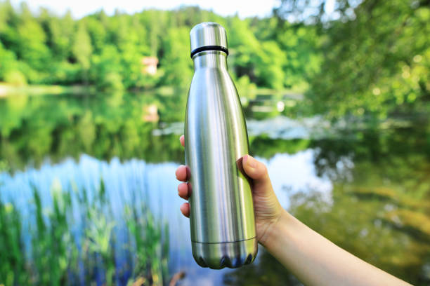 Close-up of steel eco thermo water bottle on the background of the lake in the mountains. Copy space. Zero waste, no plastic, sustainability. Close-up of steel eco thermo water bottle on the background of the lake in the mountains. Copy space. Zero waste, no plastic, sustainability. blue reusable water bottle stock pictures, royalty-free photos & images