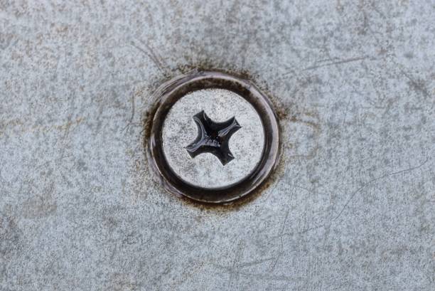 one screwed wet iron bolt into a gray frayed metal wall