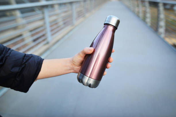 再利用可能な、水のためのスチール熱光沢のあるボトルを保持する女性の手のクローズアップ。コピー空間コンセプト。自転車レーンの水用ボトルスチール。 - water bottle 写真 ストックフォトと画像