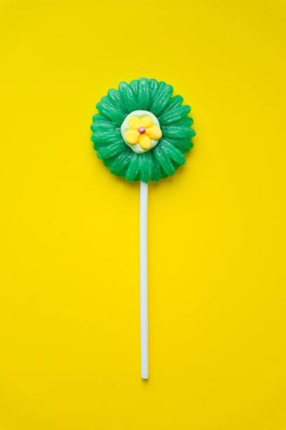 sucette en forme de fleur sur fond jaune. lollipop candy vue du dessus. - flavored ice lollipop candy affectionate photos et images de collection