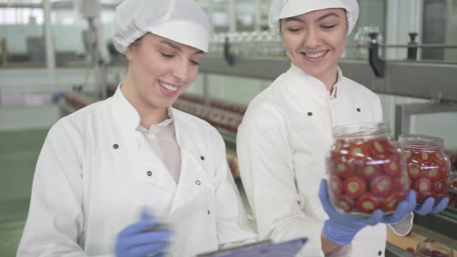 Female Workers Checking Weight Of Jars Full With Stuffed Peppers In Factory
