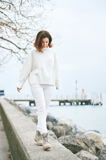 Portrait of beautiful woman spending day outside by lakeside, wearing white clothes