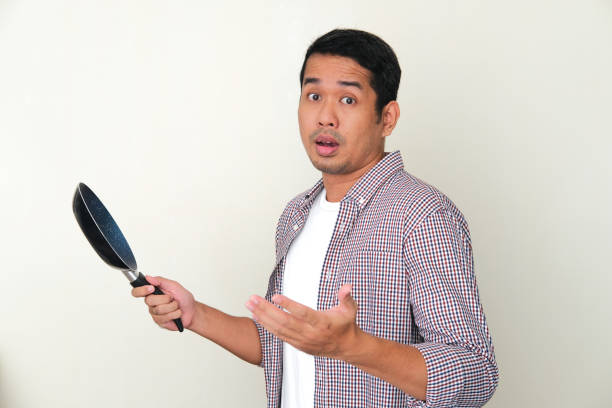 istock Adult Asian man showing confused face expression while holding frying pan 1361190810