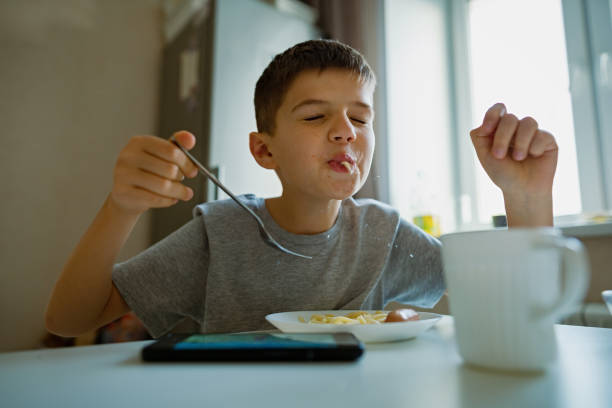 istock Cheerful, hungry boy eats pasta with appetite, sucks in pasta playfully 1361198421