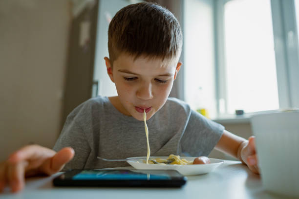 istock Boy, child eats pasta sucking long pasta into his mouth 1361198423