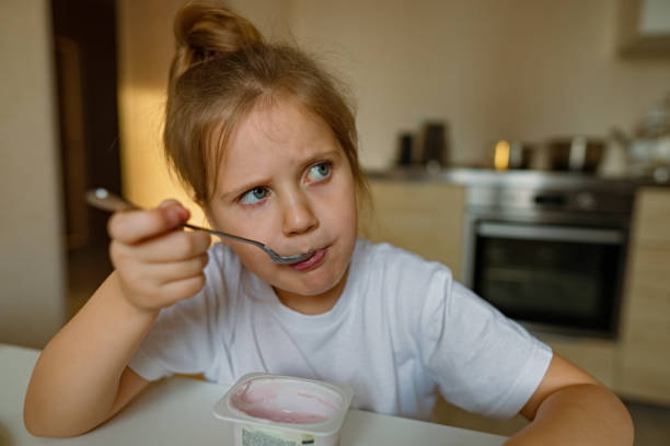 istock Cute girl eats yogur with appetite, has dirty mouth, has fun, grimaces 1361198431