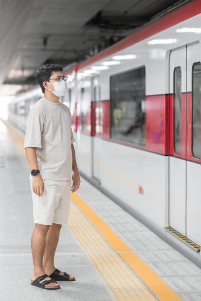 man wearing Protective face mask prevention coronavirus inflection during waiting train. public transportation. social distancing, new normal and safety under covid-19 pandemic