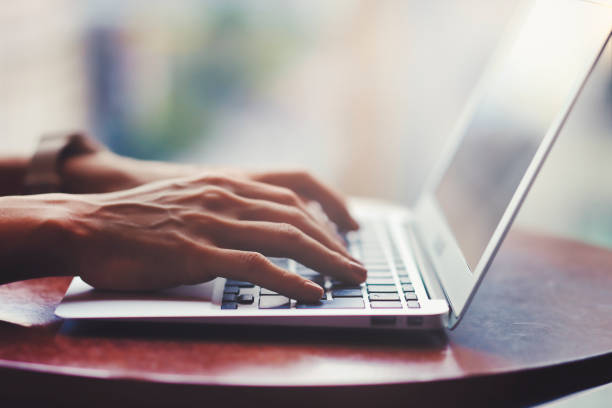 istock Hands of a person using a laptop by the window 1361213223