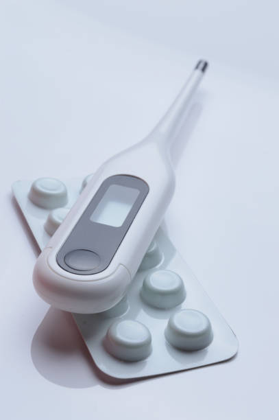 istock tablets in a package and a white electronic thermometer on a white surface close-up. 1361216059