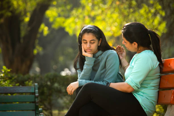 istock Mother comforting her stressed daughter at park 1361216224