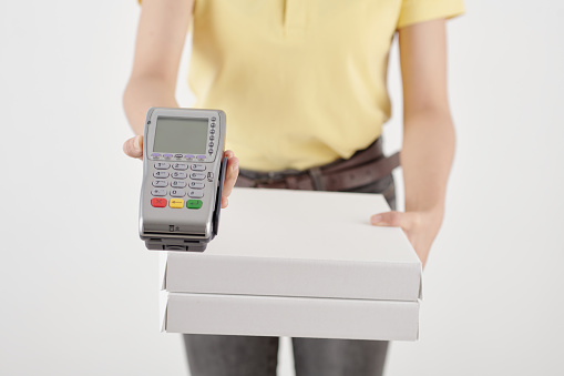Cropped image of female courier with pizza boxes giving credit card reader
