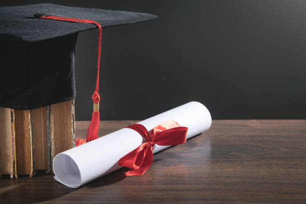 istock Graduation hat, book and diploma on the wooden table. 1361246394