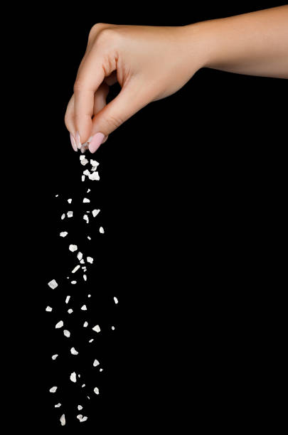 istock Sea salt falling from finger tips isolated on black 1361252888