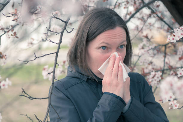 istock Woman sneezing in front of blooming cherry tree in spring 1361258729