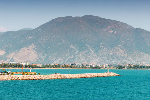 faro de navegación para yates y barcos de pesca en el espigón cerca de la ciudad de finike en turquía. las montañas de tauro se elevan en la distancia - arrival beacon blue nautical vessel fotografías e imágenes de stock