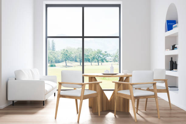 istock White dining room interior with chairs and sofa near window, art bookshelf 1361272975