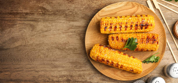istock Delicious grilled corn cobs and space for text on wooden table, flat lay. Banner design 1361273011