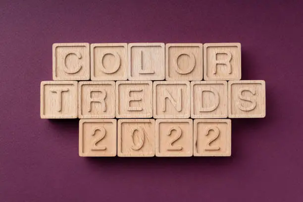 Photo of Color trends 2022, flat, lay, top view. The inscription is made of eco-friendly wooden cubes. The text is the color of the season on a burgundy background. Bright concept of trends 2022