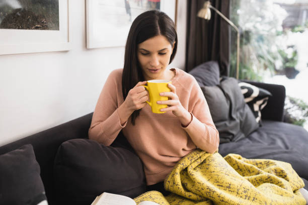 istock Woman reading and drinking coffee on the cozy sofa 1361279045