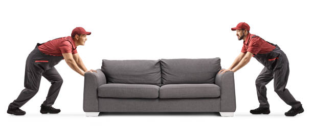 istock Two male workers moving a grey sofa isolated on white background 1361281410