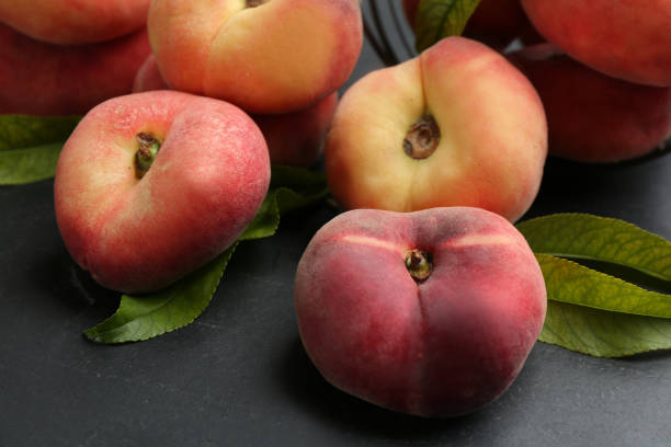 istock Fresh ripe donut peaches with leaves on dark table, closeup 1361282585